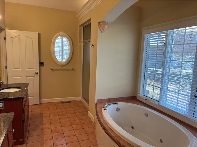 bathroom with vanity, tile flooring, a healthy amount of sunlight, and tiled tub