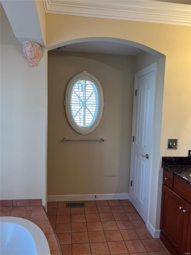 bathroom with crown molding, tile flooring, a bathtub, and vanity