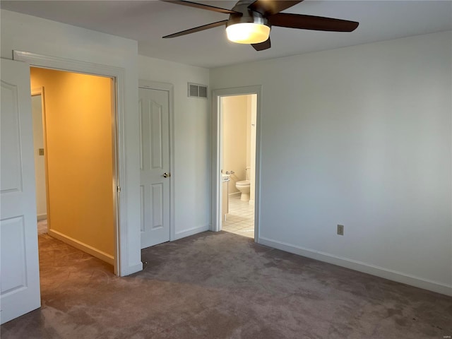 unfurnished bedroom with ensuite bathroom, a closet, ceiling fan, and dark carpet