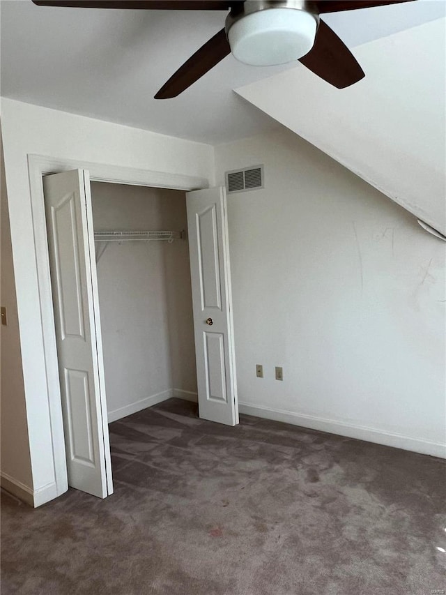 unfurnished bedroom featuring a closet, dark colored carpet, ceiling fan, and vaulted ceiling