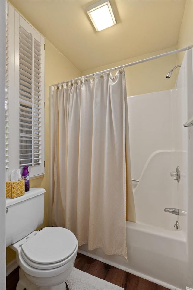 bathroom featuring toilet, hardwood / wood-style flooring, and shower / bathtub combination with curtain