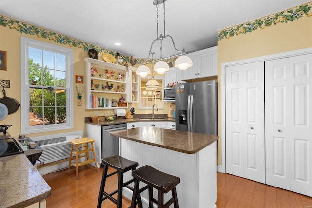 kitchen featuring light wood-type flooring, white cabinetry, stainless steel appliances, sink, and hanging light fixtures