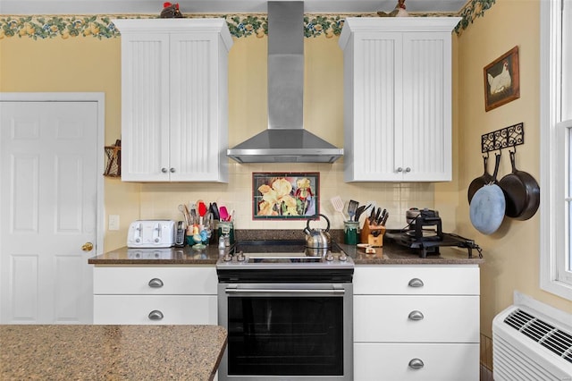 kitchen featuring backsplash, wall chimney exhaust hood, white cabinetry, and stainless steel range with electric stovetop