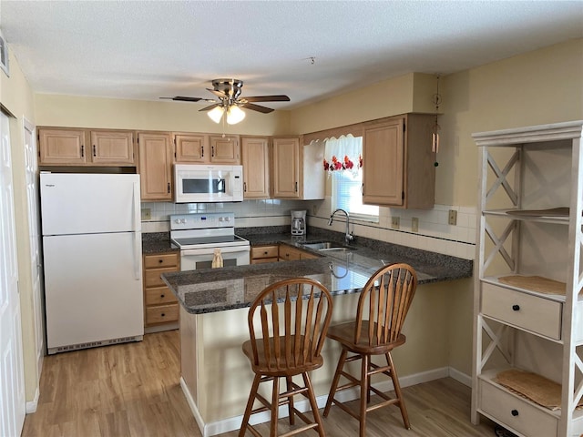 kitchen featuring kitchen peninsula, white appliances, sink, ceiling fan, and light hardwood / wood-style flooring