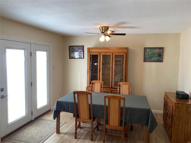 dining area featuring a textured ceiling, ceiling fan, and light wood-type flooring