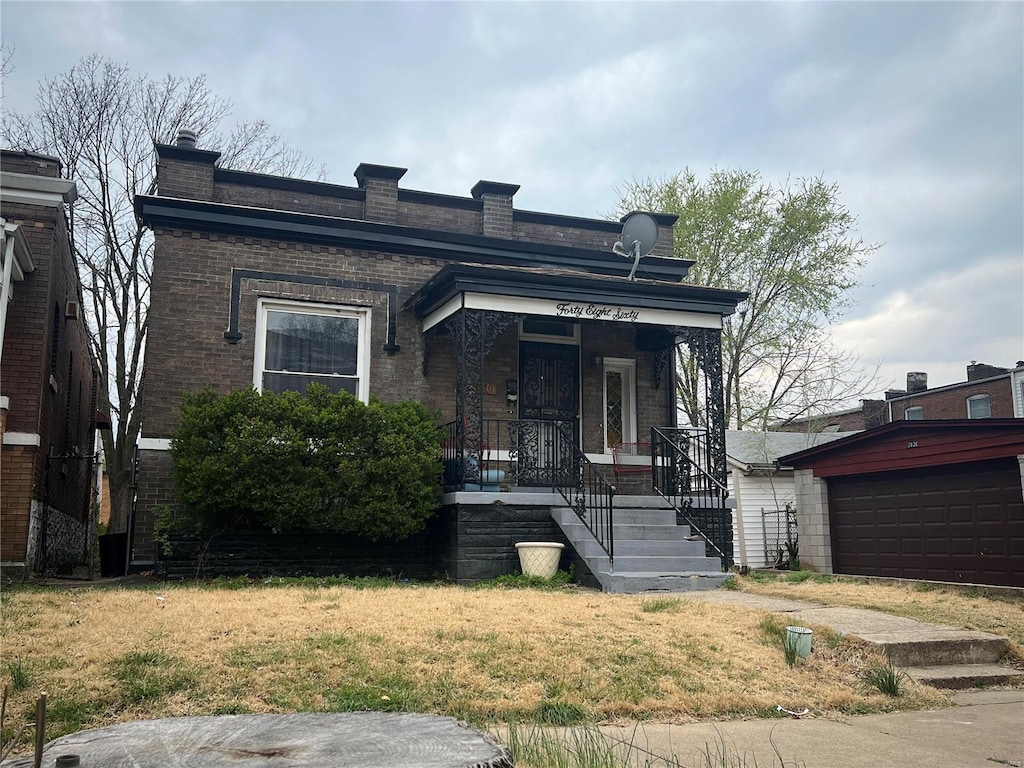 view of front of property with covered porch, a front yard, and a garage