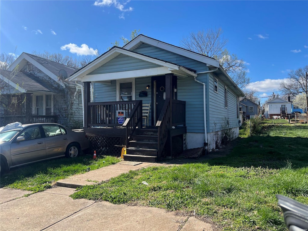 bungalow-style home with a front yard and covered porch