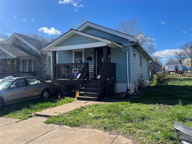 bungalow-style home with a front yard and covered porch