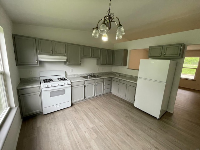 kitchen with white appliances, sink, decorative light fixtures, light hardwood / wood-style flooring, and a chandelier