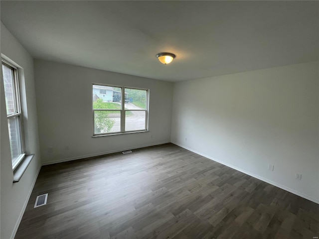 spare room featuring dark wood-type flooring and a healthy amount of sunlight