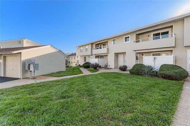 townhome / multi-family property with a balcony, a front yard, and a garage