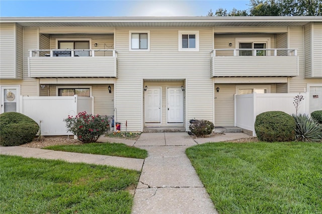 townhome / multi-family property featuring a balcony and a front lawn