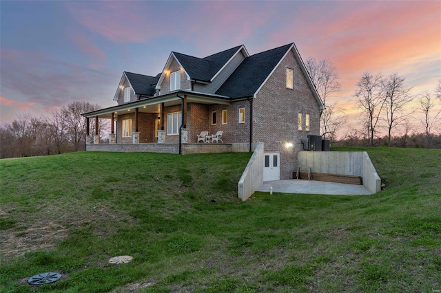 property exterior at dusk featuring a yard and a patio area