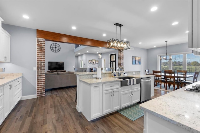 kitchen featuring stainless steel dishwasher, brick wall, dark wood-type flooring, white cabinets, and hanging light fixtures