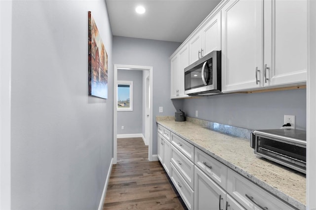 kitchen featuring dark hardwood / wood-style flooring, white cabinetry, and light stone countertops