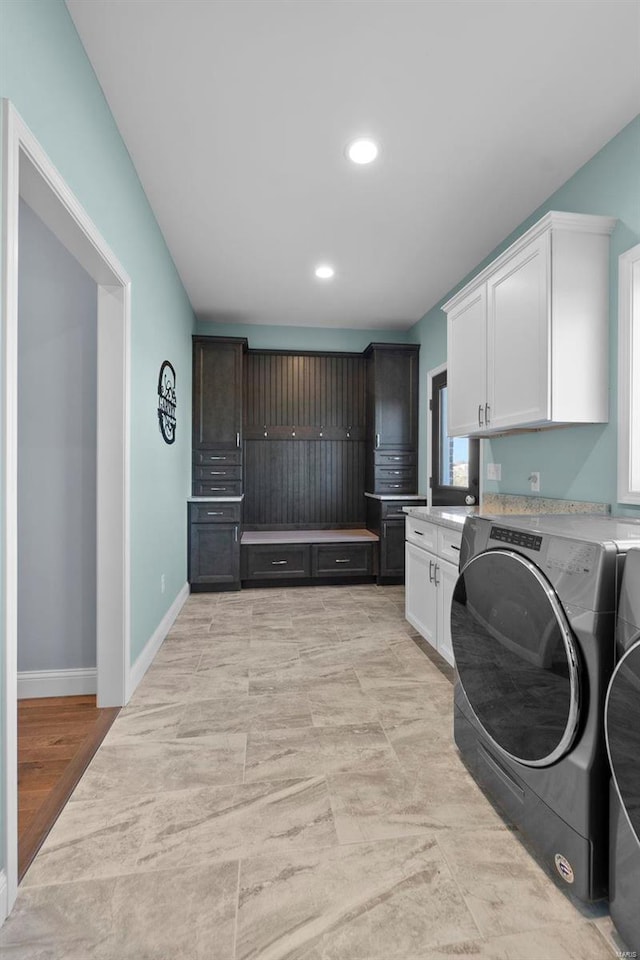 washroom featuring washing machine and clothes dryer, cabinets, and light tile floors