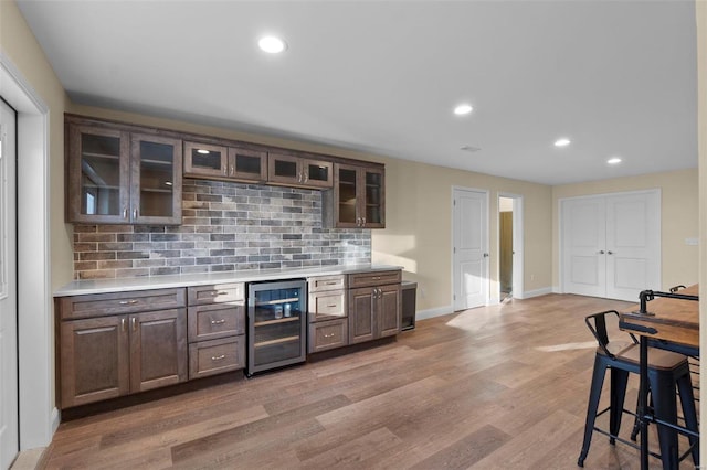 kitchen with backsplash, light hardwood / wood-style flooring, dark brown cabinetry, and wine cooler