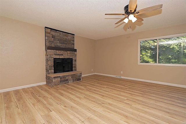 unfurnished living room with a fireplace, a textured ceiling, light hardwood / wood-style floors, and ceiling fan