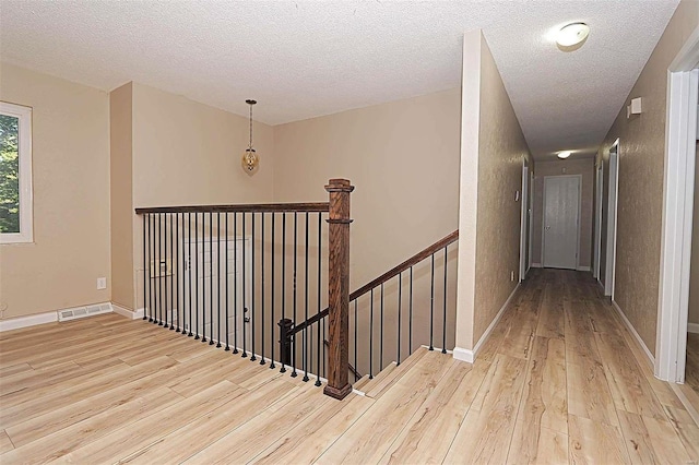 hallway featuring a textured ceiling and light wood-type flooring