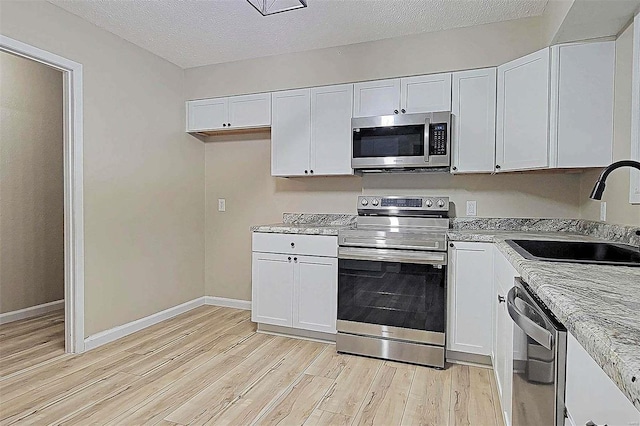 kitchen featuring light hardwood / wood-style floors, stainless steel appliances, and white cabinets