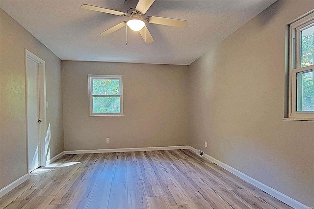 empty room featuring ceiling fan, light wood-type flooring, and plenty of natural light