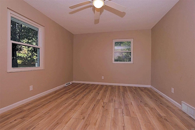 spare room with a healthy amount of sunlight, a textured ceiling, light hardwood / wood-style floors, and ceiling fan