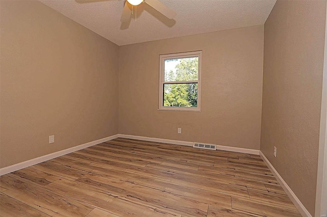 unfurnished room with a textured ceiling, wood-type flooring, and ceiling fan