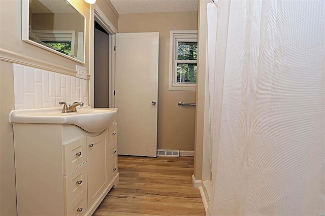 bathroom with vanity, a textured ceiling, hardwood / wood-style flooring, and a wealth of natural light