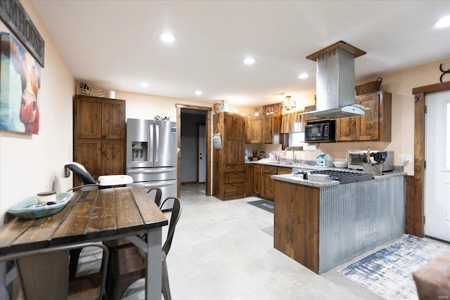 kitchen featuring light stone countertops, kitchen peninsula, island range hood, stainless steel refrigerator with ice dispenser, and sink