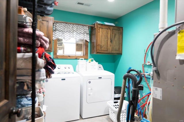 laundry area featuring washing machine and clothes dryer and cabinets