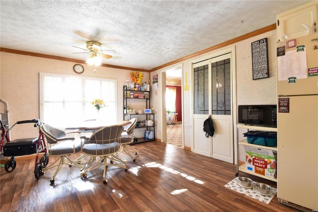 dining area featuring hardwood / wood-style floors, ceiling fan, ornamental molding, and a textured ceiling