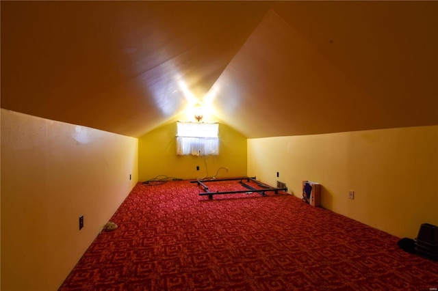 additional living space featuring lofted ceiling and dark colored carpet