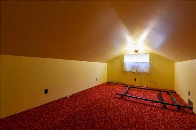 additional living space featuring dark colored carpet and lofted ceiling