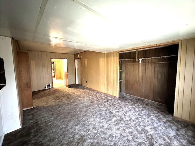 carpeted spare room featuring wood walls