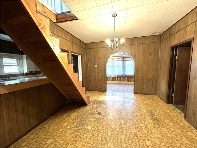 kitchen with a wealth of natural light, wood walls, a chandelier, and light tile floors