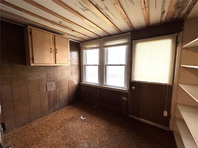 empty room featuring wooden walls, dark carpet, and wood ceiling