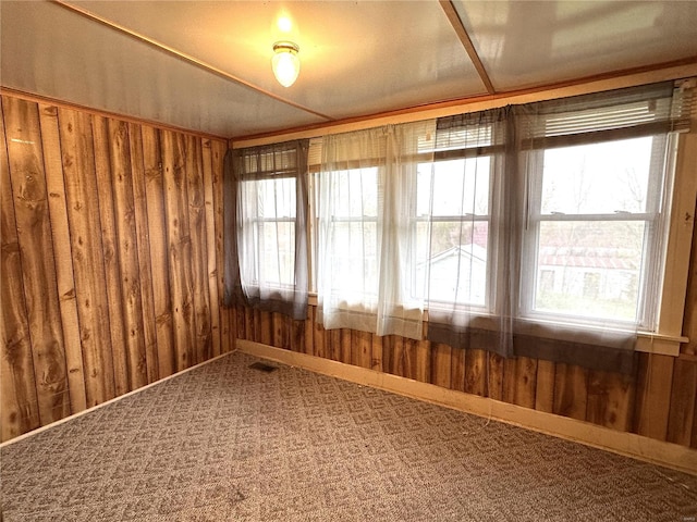 unfurnished room with carpet floors and wood walls