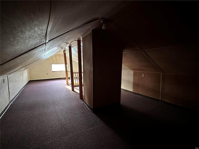 additional living space with dark carpet and vaulted ceiling