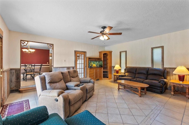 tiled living room featuring ceiling fan with notable chandelier and a textured ceiling