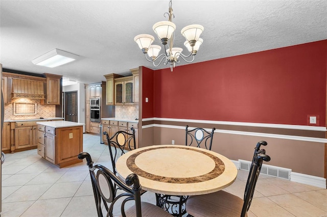 tiled dining space featuring a notable chandelier and a textured ceiling