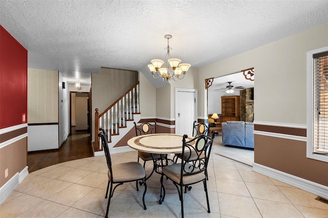 dining area with ceiling fan with notable chandelier, light wood-type flooring, and a textured ceiling