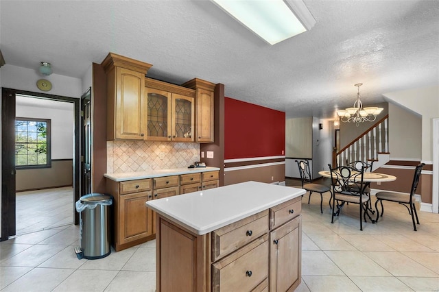 kitchen featuring a textured ceiling, backsplash, light tile patterned floors, and a center island