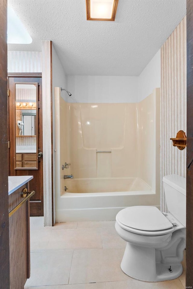 full bathroom featuring toilet,  shower combination, tile patterned floors, vanity, and a textured ceiling