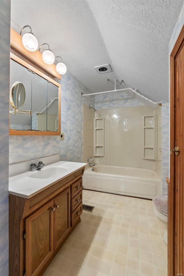 full bathroom with washtub / shower combination, vanity, toilet, and a textured ceiling