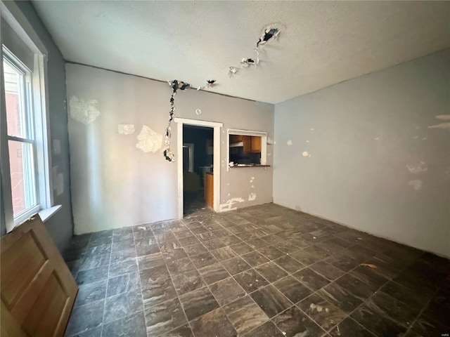 tiled empty room featuring a textured ceiling and plenty of natural light