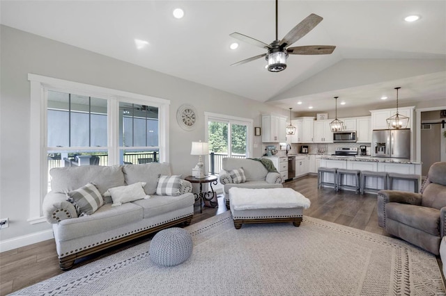 living room featuring dark hardwood / wood-style flooring, sink, lofted ceiling, and ceiling fan with notable chandelier