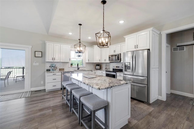 kitchen with white cabinets, a kitchen island, dark hardwood / wood-style floors, and stainless steel appliances