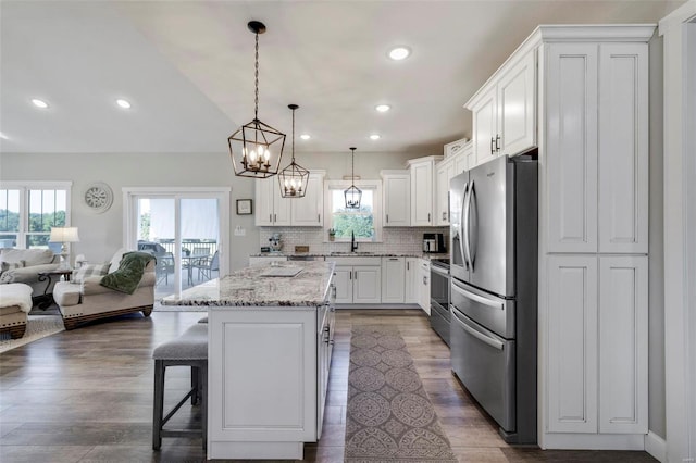 kitchen featuring decorative light fixtures, backsplash, a breakfast bar area, wood-type flooring, and stainless steel fridge with ice dispenser