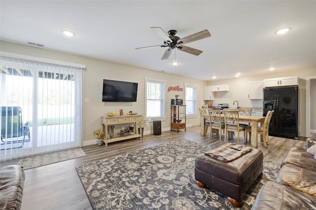 living room with ceiling fan, a wealth of natural light, and dark hardwood / wood-style floors