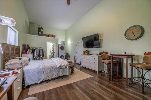 bedroom with ensuite bathroom, stacked washer / dryer, high vaulted ceiling, and dark hardwood / wood-style flooring